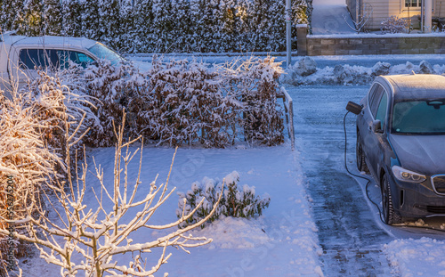 Wallpaper Mural Beautiful view of parking lot in private house with electric car connected by cable from charging station on frosty winter day. Sweden. Torontodigital.ca
