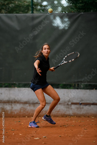 view of focused female tennis player with racket ready to hit a tennis ball.