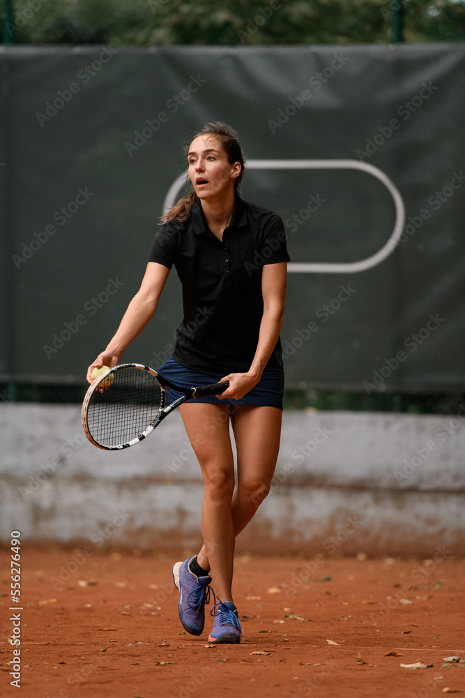 handsome female tennis player with racket and ball prepares to serve at beginning of game