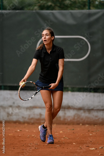 handsome female tennis player with racket and ball prepares to serve at beginning of game © fesenko