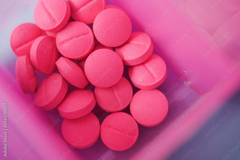 close up of pink color medical pills in a pill box on table close up of pink color medical pills in a pill box on table