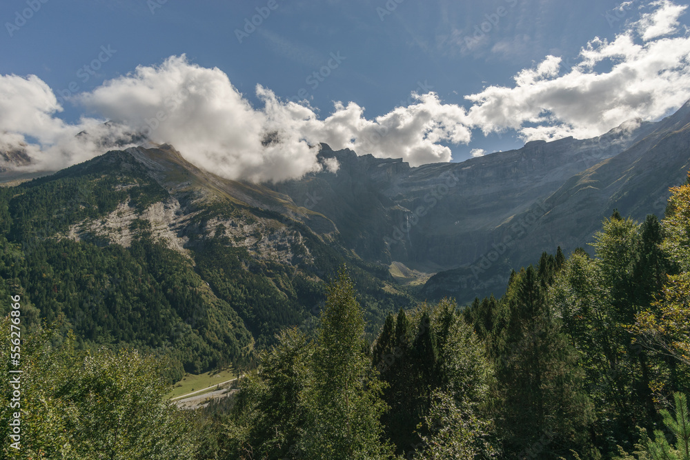 Cirque de Gavarnie with waterfall at massive high rock wall formation and forest in foreground in Pyrenees Mountains, Nouvelle-Aquitaine, France