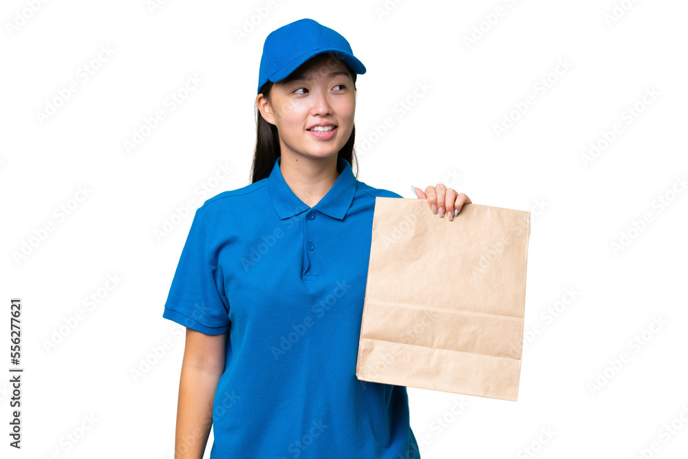 Young Asian woman taking a bag of takeaway food over isolated background looking side Young Asian woman taking a bag of takeaway food over isolated background looking side