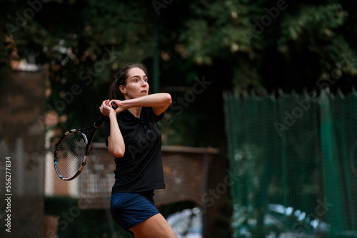 view of sporty woman with tennis racket and with concentrated expression on her face