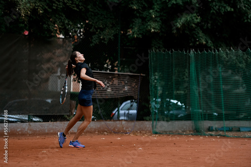 side view of active woman tennis player with tennis racket in her hand behind her back © fesenko