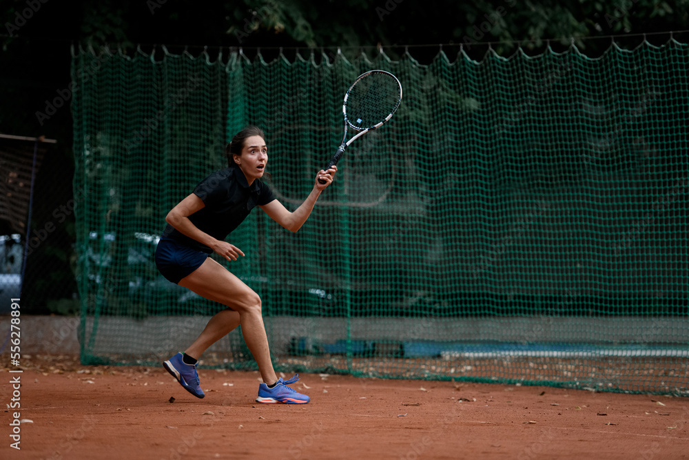 view of active woman with excited expression with tennis racket in hand ready to hit the ball view of active woman with excited expression with tennis racket in hand ready to hit the ball