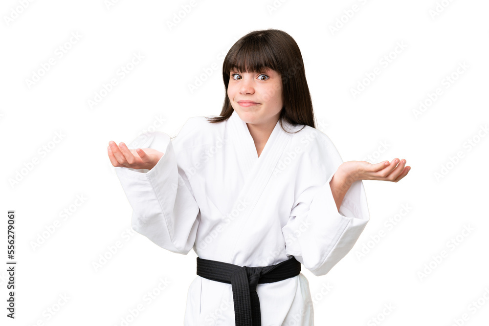 Little Caucasian girl doing karate over isolated background having doubts while raising hands Little Caucasian girl doing karate over isolated background having doubts while raising hands