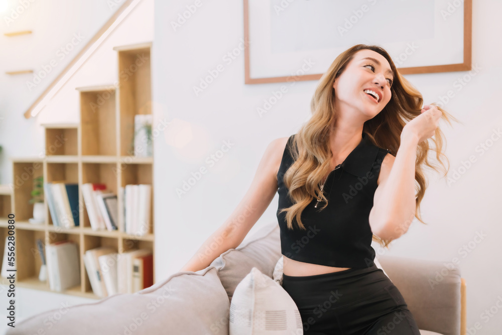 happy woman spreading long hair by hand. cheerful female shaking head looking away relax in living room. relax smiling pretty beautiful modeling woman sitting posing on soft couch spreading hair flow happy woman spreading long hair by hand. cheerful female shaking head looking away relax in living room. relax smiling pretty beautiful modeling woman sitting posing on soft couch spreading hair flow