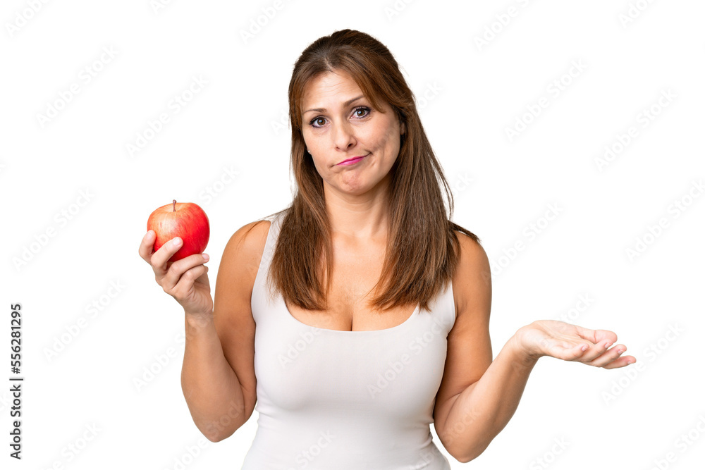 Middle age woman with an apple over isolated background making doubts gesture while lifting the shoulders Middle age woman with an apple over isolated background making doubts gesture while lifting the shoulders