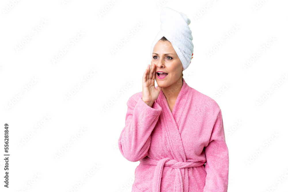 Middle age caucasian woman in a bathrobe over isolated background shouting with mouth wide open to the lateral Middle age caucasian woman in a bathrobe over isolated background shouting with mouth wide open to the lateral