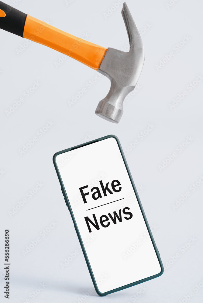 Claw hammer breaking smartphone with inscription Fake News. Creative concept no lies, rejection of untruth news, propaganda Claw hammer breaking smartphone with inscription Fake News. Creative concept no lies, rejection of untruth news, propaganda