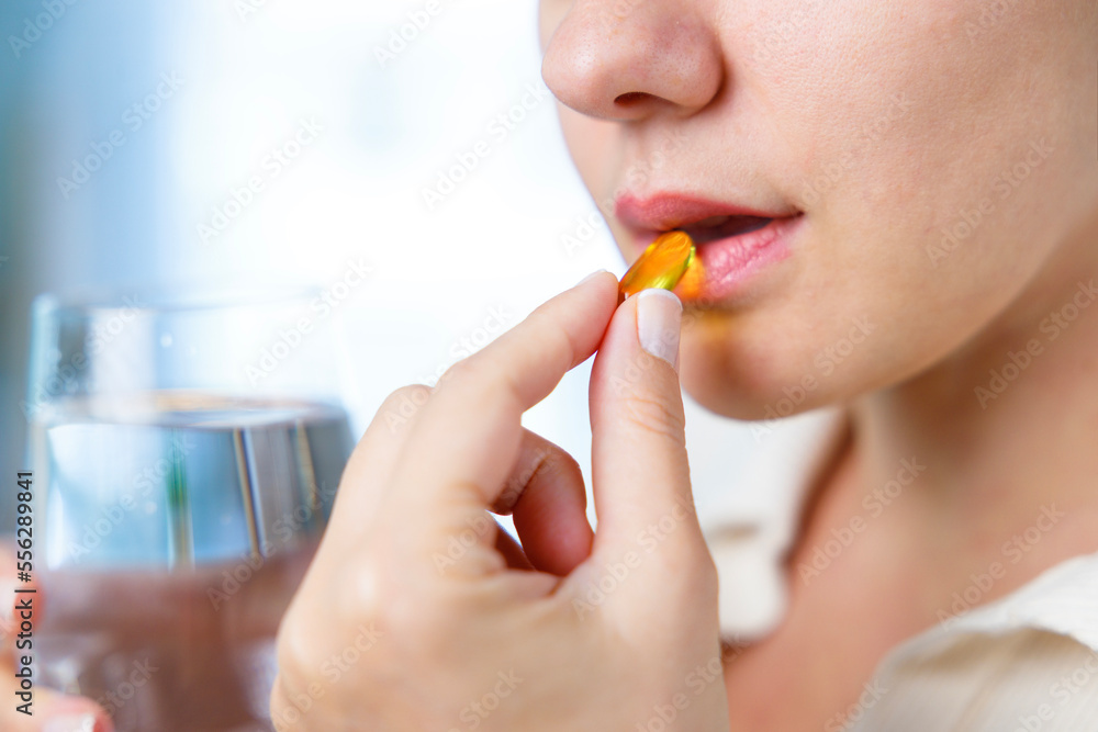 Young woman taking Omega 3 capsule Young woman taking Omega 3 capsule