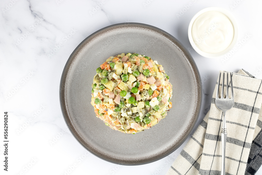 Russian Olivier salad of vegetables, sausage and mayonnaise on a white background. Top view. Russian Olivier salad of vegetables, sausage and mayonnaise on a white background. Top view.