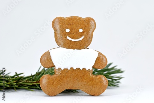Smiling gingerbread bear with spruce twig, white background