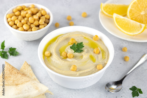 Chickpea hummus with pita, olive oil, parsley and lemon on a gray background. Arabic, Turkish cuisine.