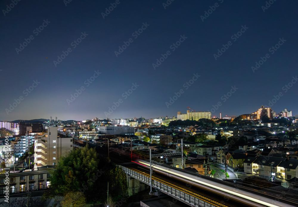 Train moves through quiet cityscape at night
