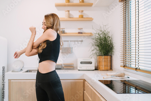 happy woman stretching improve arms movement. smiling pretty woman warming before or after exercising reduce muscle tension. beautiful woman training home fitness trying twisting arms for stretching