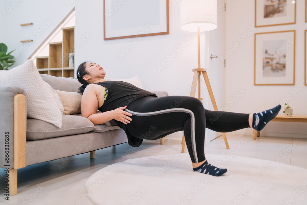 fat woman doing sofa exercise indoors living room tricep dip. motivated