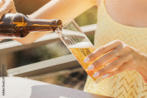 girl pours from a bottle to a glass and drinks a delicious craft traditional German and Cologne beer Kolsch in outdoor biergarten pub or cafe photo