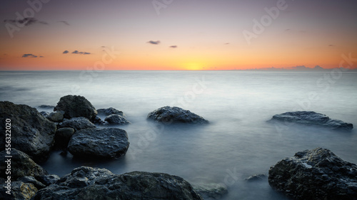 Sunset at Sea  stones on the shore  Amazing perfect pink dreamy looking sunset. Smooth water