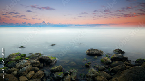 Sunset at Sea, stones on the shore, Amazing perfect pink dreamy looking sunset. Smooth water © Aleksandr Matveev