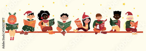 Group of little children in winter clothes reading Christmas story on light background