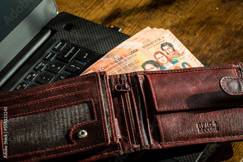 Bolivia money, a wallet full of banknotes lying on the computer keyboard photo