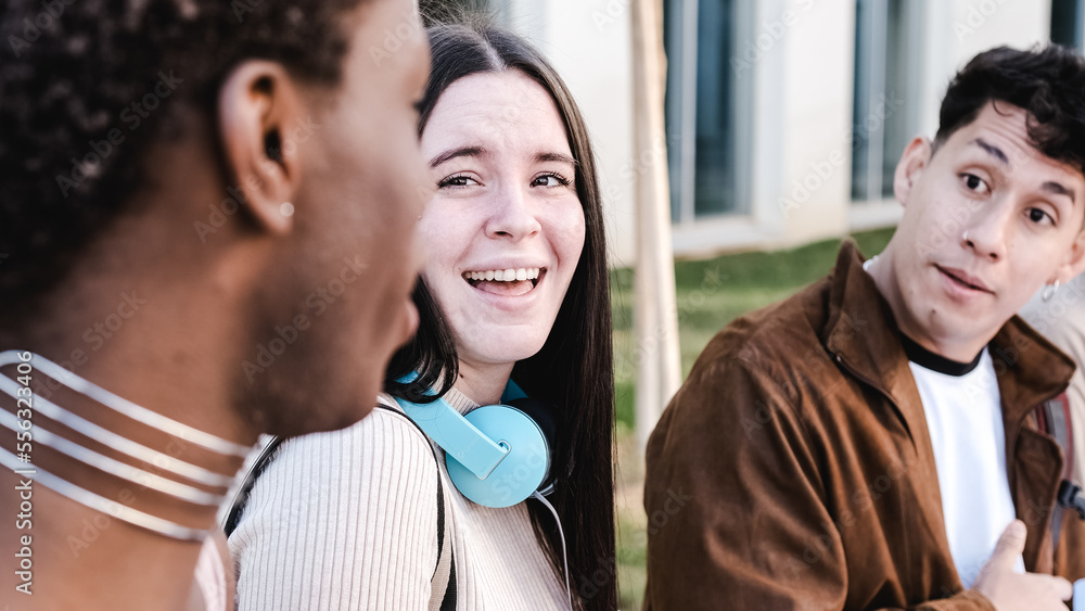 Group of multiethnic friends chatting and joking sitting outdoors Group of multiethnic friends chatting and joking sitting outdoors
