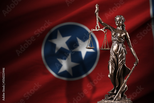 Tennessee US state flag with statue of lady justice and judicial scales in dark room. Concept of judgement and punishment, background for jury topics photo