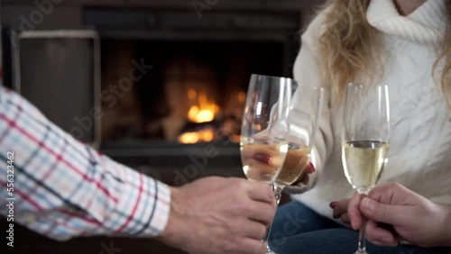 Close-up of hands clinking glasses. A small group of people clink glasses of champagne by the fireplace photo