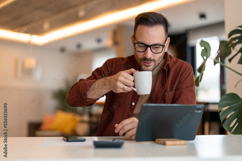 Stylish happy modern guy using tablet and drinking a cup of coffee. Photo of a male working on a tablet or reading news while drinking coffee. Stylish happy modern guy using tablet and drinking a cup of coffee. Photo of a male working on a tablet or reading news while drinking coffee.