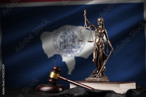 Wyoming US state flag with statue of lady justice, constitution and judge hammer on black drapery. Concept of judgement and punishment photo