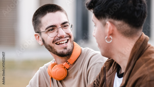 Two cool friends talking and laughing together siting outdoors