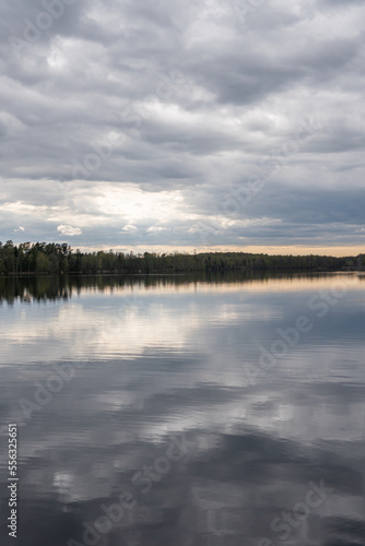 A beautiful lake in spring  dynamic grey sky  clouds. Reflection in the water. Place for rest.