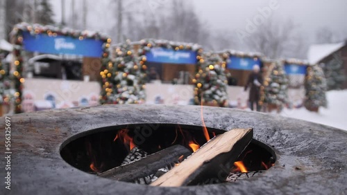 Burning coals ready for barbecue. Firewood coals for grill and BBQ, close up. Coals are burning in a round brazier against the background of Christmas lights.