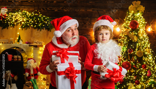 Santa Claus and little child with Christmas present at home. Family holidays and childhood concept.