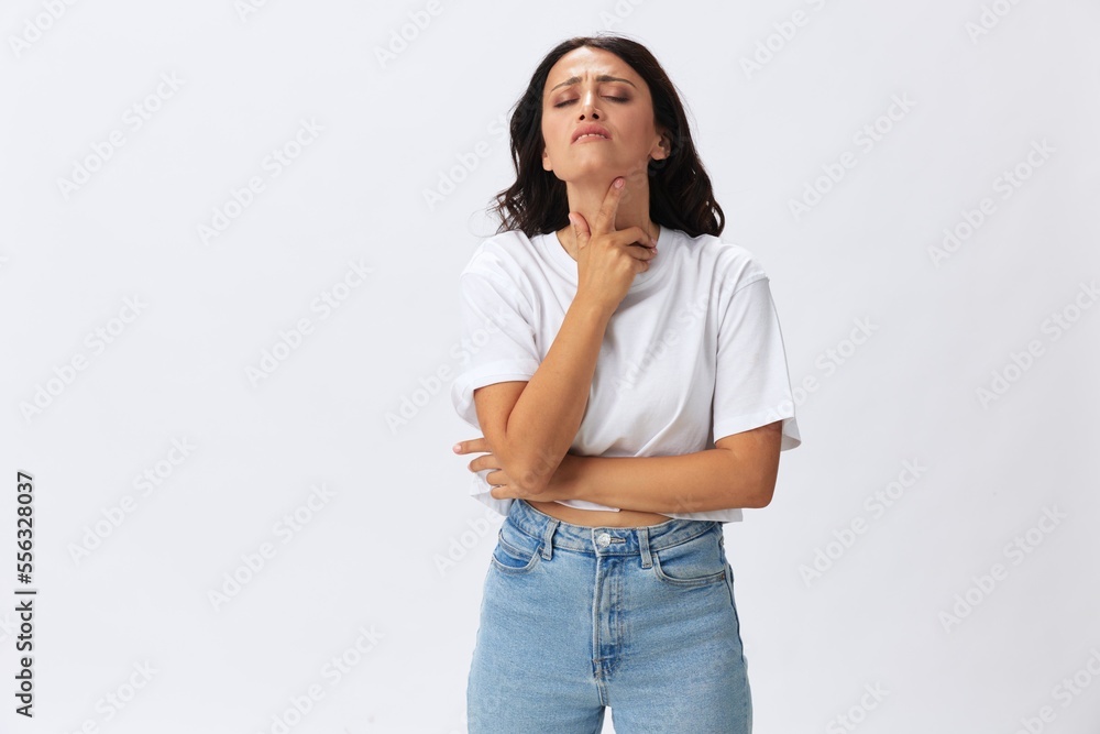 Woman sore throat and inflammation of the ligaments with a cold, a woman in a white t-shirt and jeans on a white background, copy space Woman sore throat and inflammation of the ligaments with a cold, a woman in a white t-shirt and jeans on a white background, copy space