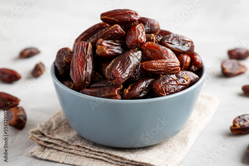 Pitted Organic Dates in Bowl on gray background, side view.