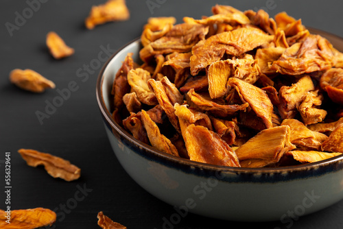 Delicious Organic Dried Mango Fruit in a Bowl on a black background, side view. © Liudmyla
