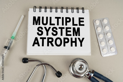On a gray surface there is a syringe, a stethoscope and a notepad with the inscription - Multiple system atrophy