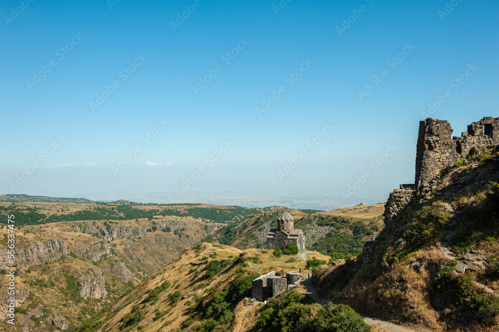 Ancient Christian temple in the mountains and the walls of the ruined fortress. Armenian holy and tourist place. Monument of culture, religion and history