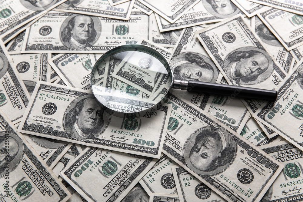 Dollar bills and a magnifying glass Dollar bills and a magnifying glass