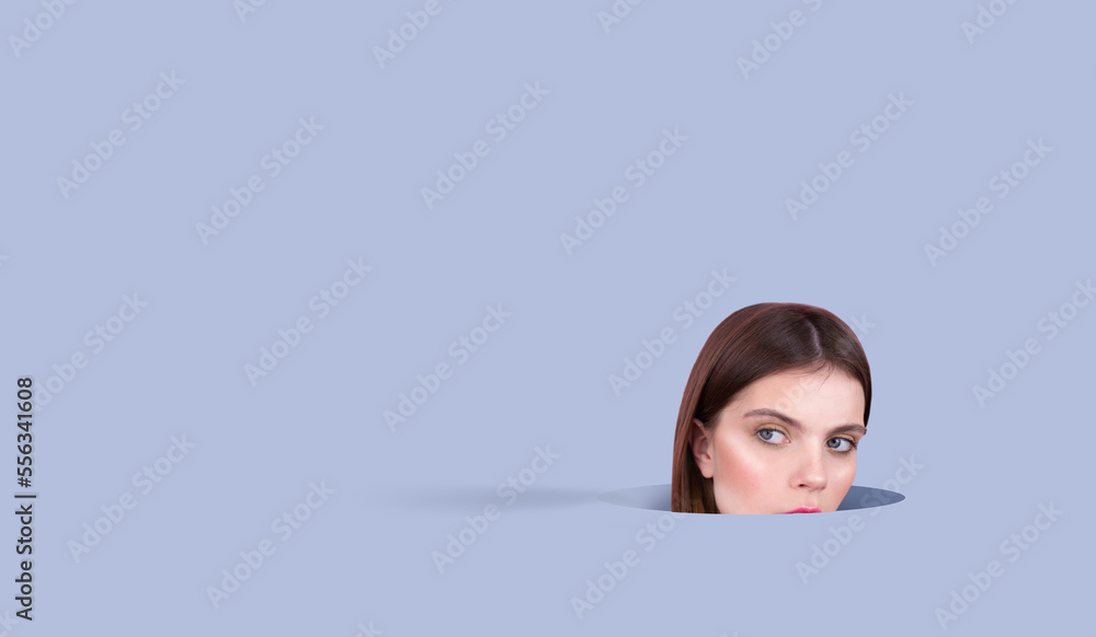 Close-up Android face of young woman with BLUE EYES natural make-up, head sticking out of a hole in the background isolated, blue background Spays for infographics or text Close-up Android face of young woman with BLUE EYES natural make-up, head sticking out of a hole in the background isolated, blue background Spays for infographics or text