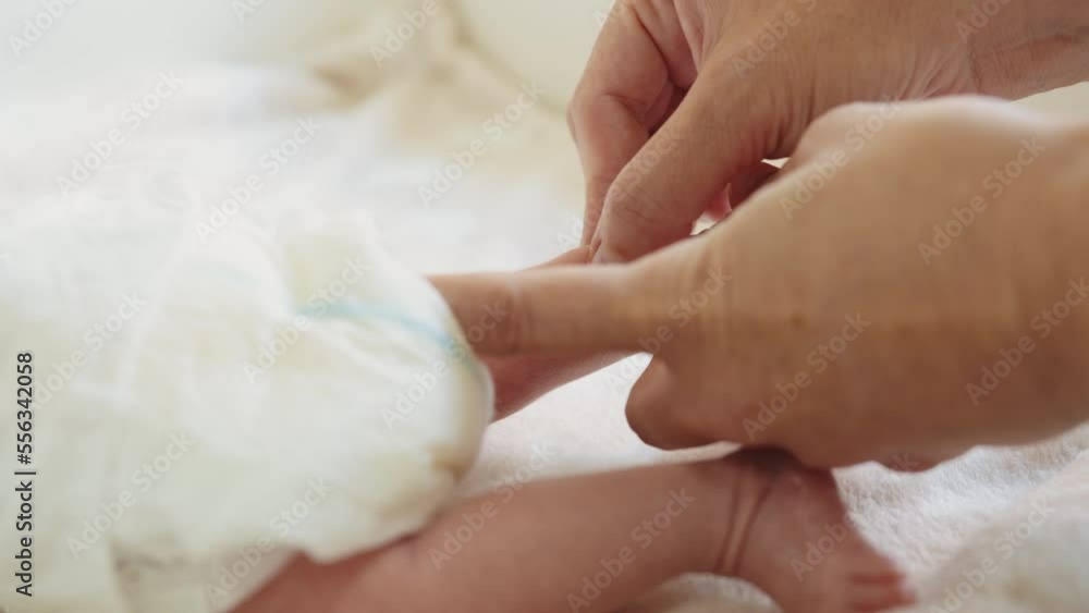 Hands of therapist rubs the small leg of infant. Masseur massaging little baby's foot. Childhood concept. Stay home. Foot massage. Close-up baby foot massage on the bed Hands of therapist rubs the small leg of infant. Masseur massaging little baby's foot. Childhood concept. Stay home. Foot massage. Close-up baby foot massage on the bed