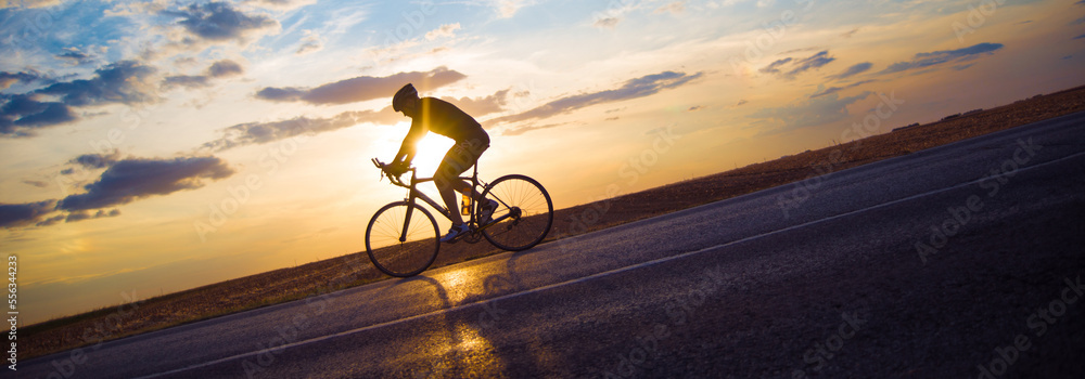 © Solid photos - Young sports man cycling with bicycle on the road in summer