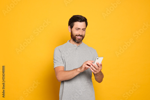 Happy man with smartphone on yellow background