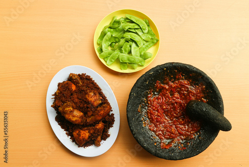 Ayam Goreng Lengkuas or Galangal Fried Chicken or Ayam Serundeng with chili sauce or sambal cobek and kacang roay (Phaseolus lunatus) as a vegetable. Indonesian dish concept photo