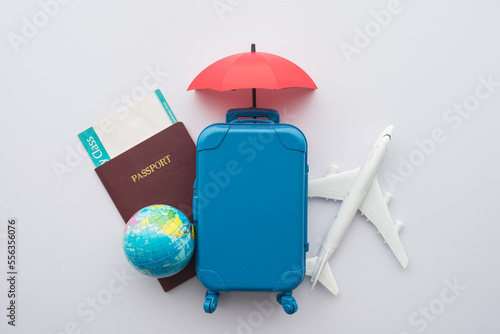 Red umbrella cover airplane, passport, globe, flight tickets and suitcases travelers on white background. Travel insurance covers loss suitcase, flight delays, cancellation, accident, medical expenses