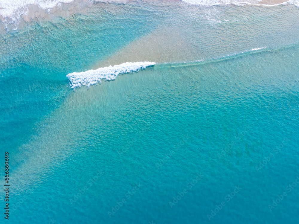 Obraz premium Beautiful sea waves water surface,Beach Sand Sea Shore and waves white foamy summer sunny day background.Amazing beach top down view overhead seaside nature background