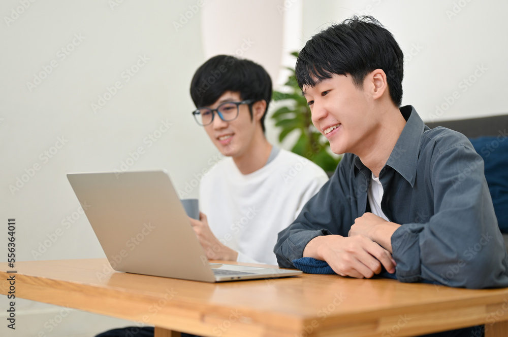 Two of smart young Asian male college students looking at laptop screen. side view Two of smart young Asian male college students looking at laptop screen. side view